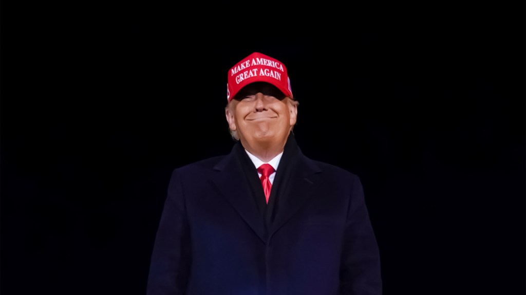 donald trump wearing maga hat in a dark background